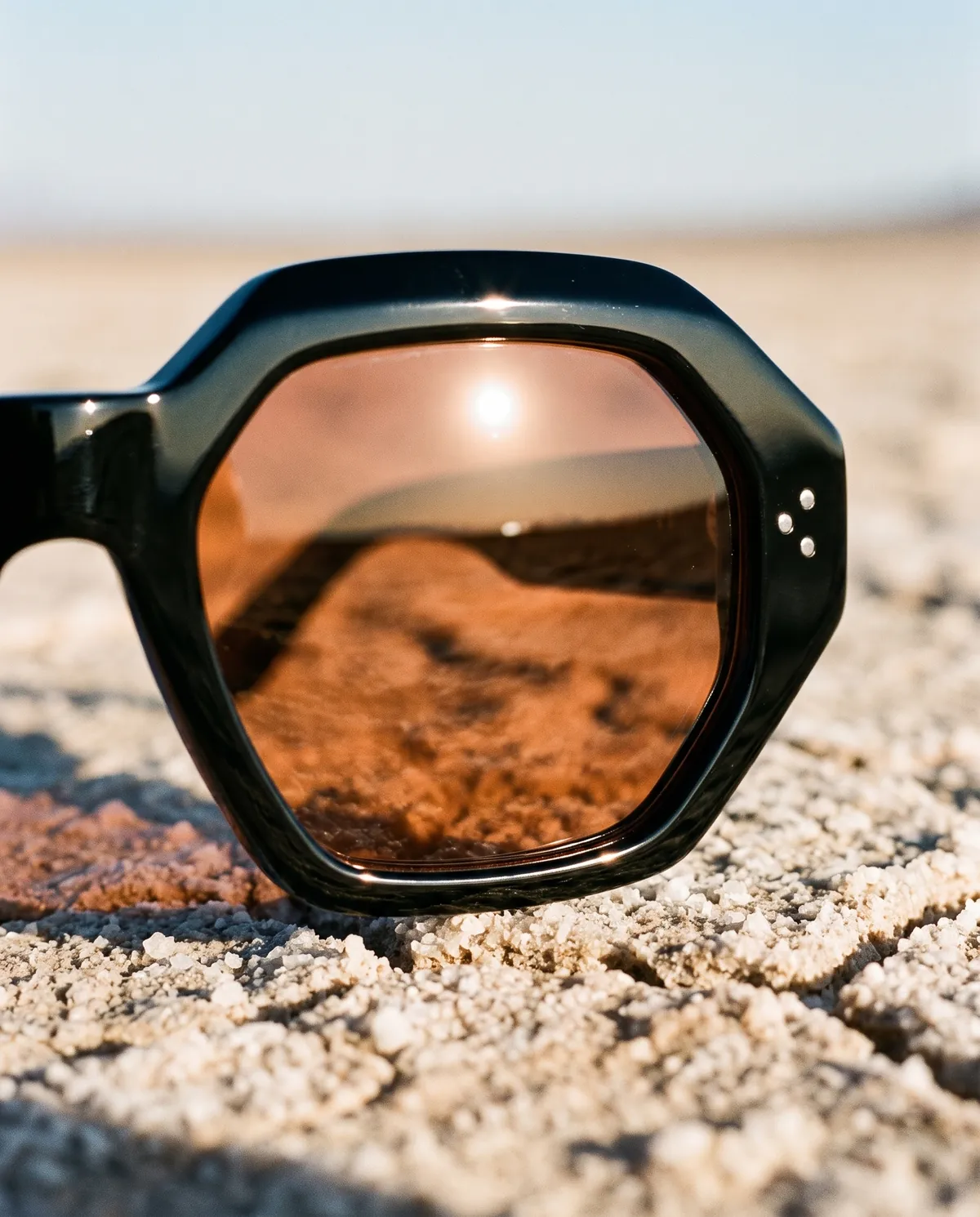 Macro of the Shard copper lens reflecting the desert horizon and sun